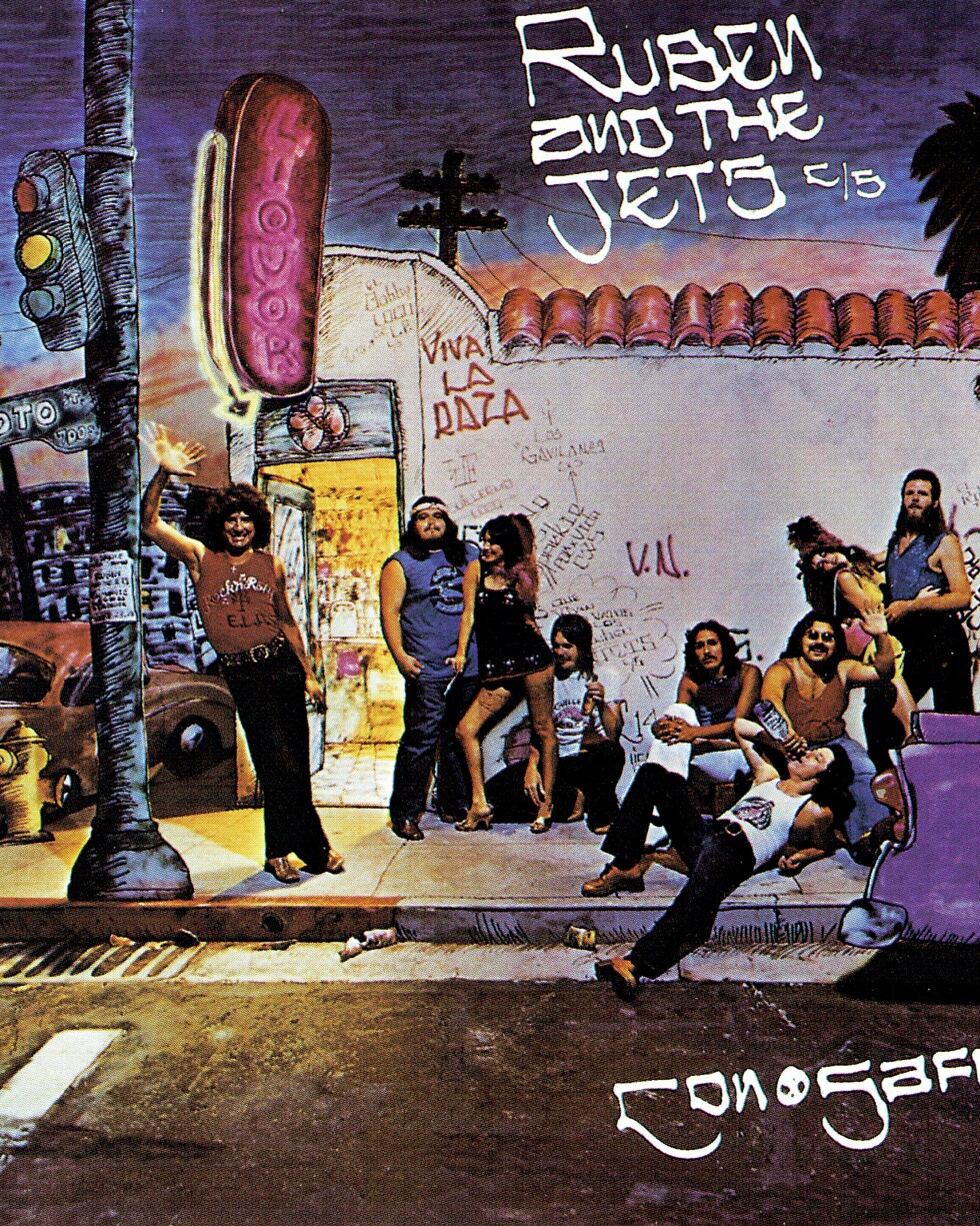 An illustration of a street corner in Los Angeles with men and women hanging out. On the side, there is graffiti that says "Viva La Raza." The album title is "Ruben and the Jets."