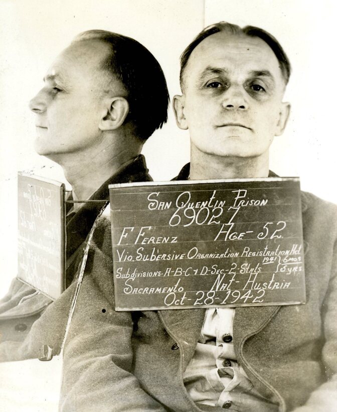 A black and white archival photo depicts a mugshot of Franz Ferenz. It's a composited photo, duplicating Franz in two positions. The first is Franz looking directly to the camera while the other is a profile shot. He's holding an identification card that reads "San Quentin Prison, 6902, F. Franz. Age 52, Via subversive organization resistance, Sacramento, Nat Austria, Oct -28-1942.