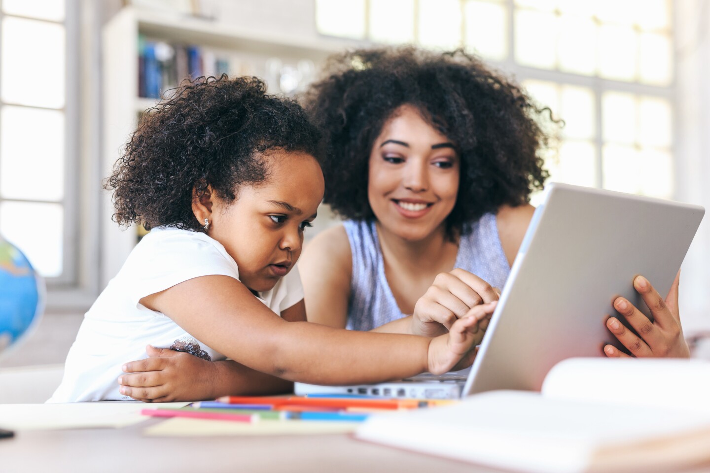 A young mother and child work on a computer together. iStock