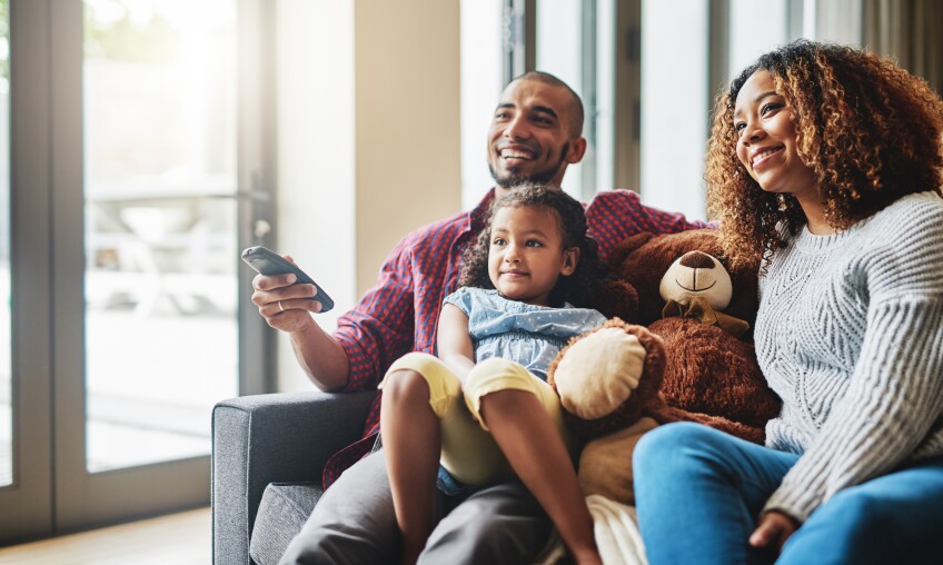 Cropped shot of a happy young family of three watching tv together in their living room at home