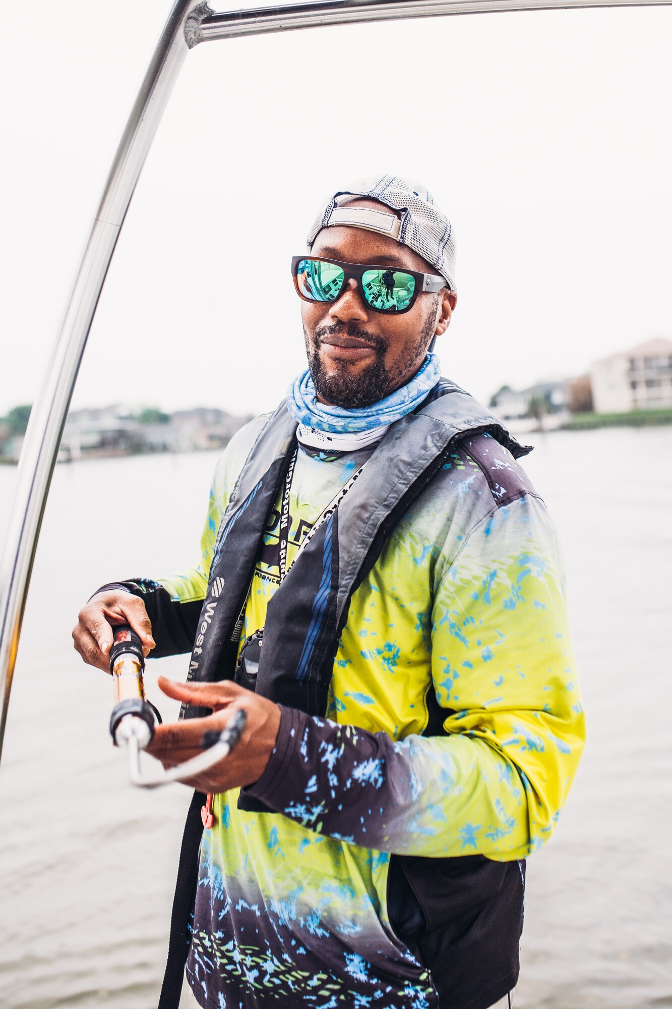 A man stands on a fishing boat. Behind him is a view of Clear Lake, Texas.