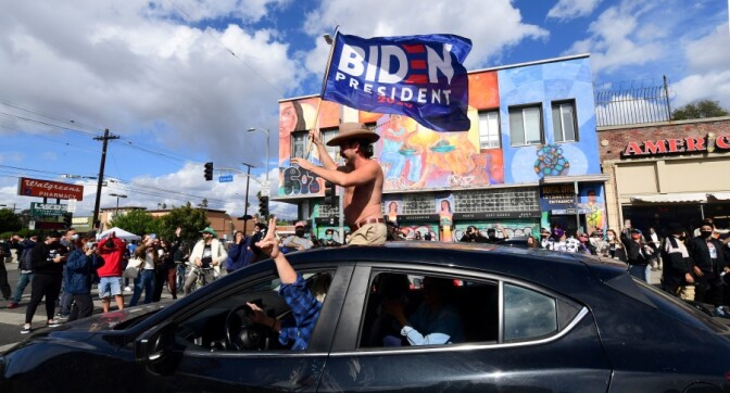 A man waves a Biden flag from his car as people take to the streets in Los Angeles on Nov. 7, 2020 to celebrate Joe Biden and the Democratic Party's victory in the 2020 presidential election. | Frederic J. Brown/AFP via Getty Images