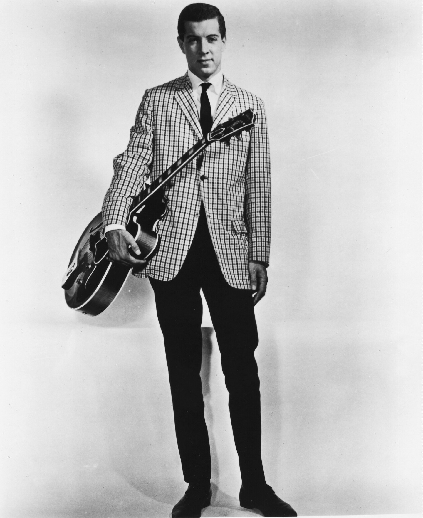 Kenny Burrell, pictured as a young man with a guitar wearing a suit.
