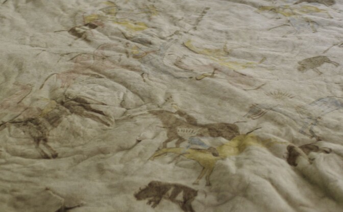 A still from "Artbound" episode "Imagined Wests" reveals an 19th century robe laid flat on a surface. The material is a light beige color and features faded illustrations of horses.
