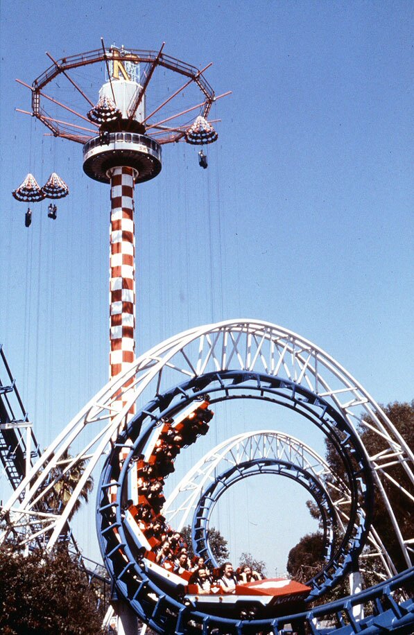 In the 1970s, roller coasters made their first appearance inside Knott's Berry Farm. This photo from circa 1980 shows the Corkscrew roller coaster in front of the Parachute Sky Jump ride. Courtesy of the Orange County Archives.