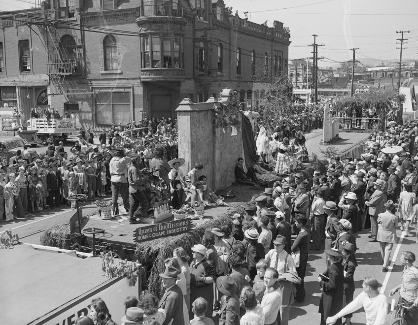 Children dressed as Mission Indians smile with baskets of grapes on this float.