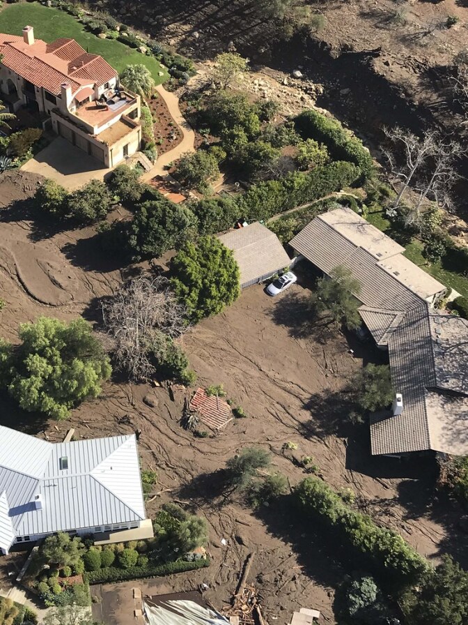 Aerial photo of houses impacted by the mud slide with roofs showing.