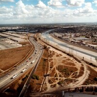The cement-confined Los Angeles River, right, slides past open industrial lots in Los Angeles, CA