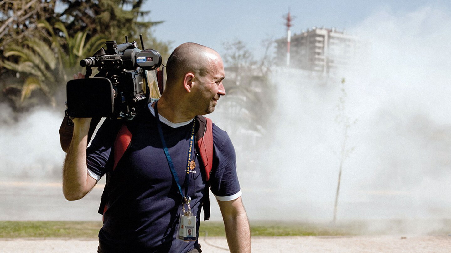 Al Jazeera English News Hour director of photography looking back at a dusty scene.