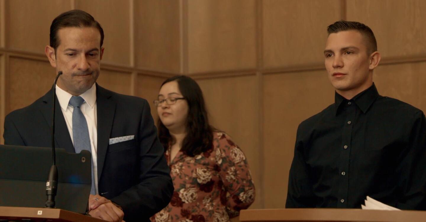 A lawyer grimaces at something with his client by his side. | From "The Definition of Insanity"