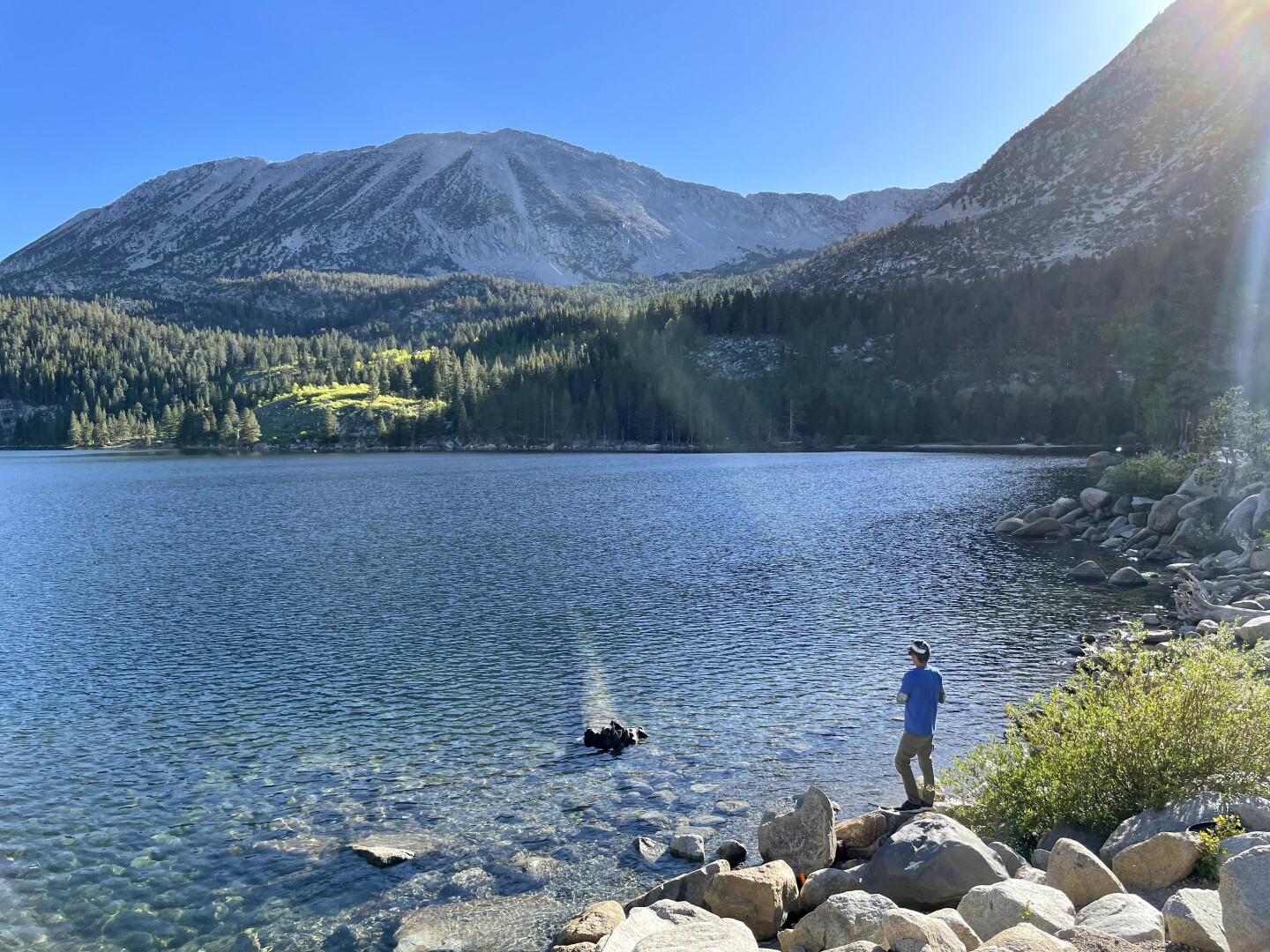 A man looks out into a peaceful lake.