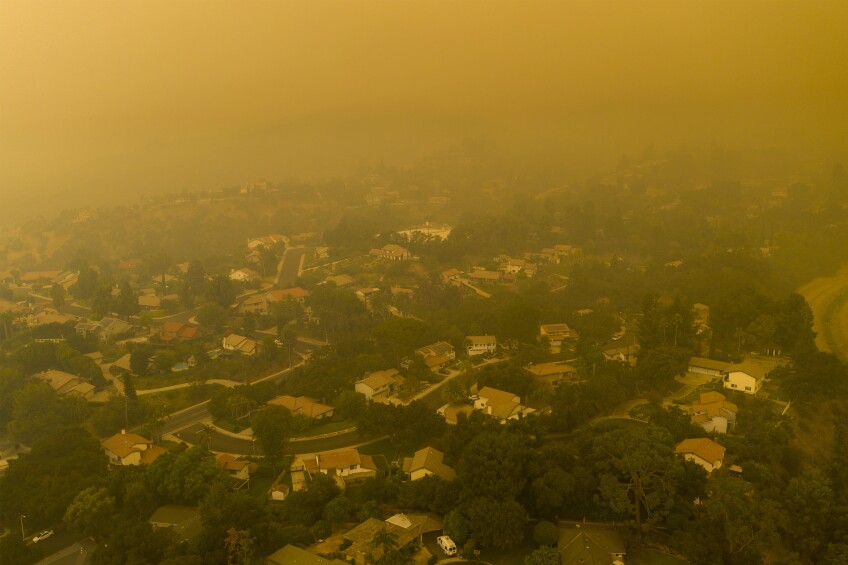 an overview of a neighborhood of houses and trees covered in orange smoke