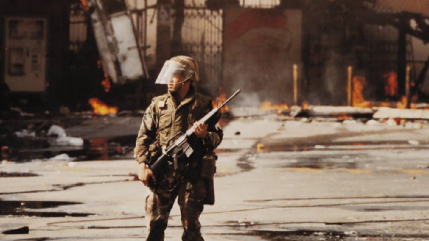 Cover of a publication featuring a police officer in riot gear beneath the words "Understanding the Riots"