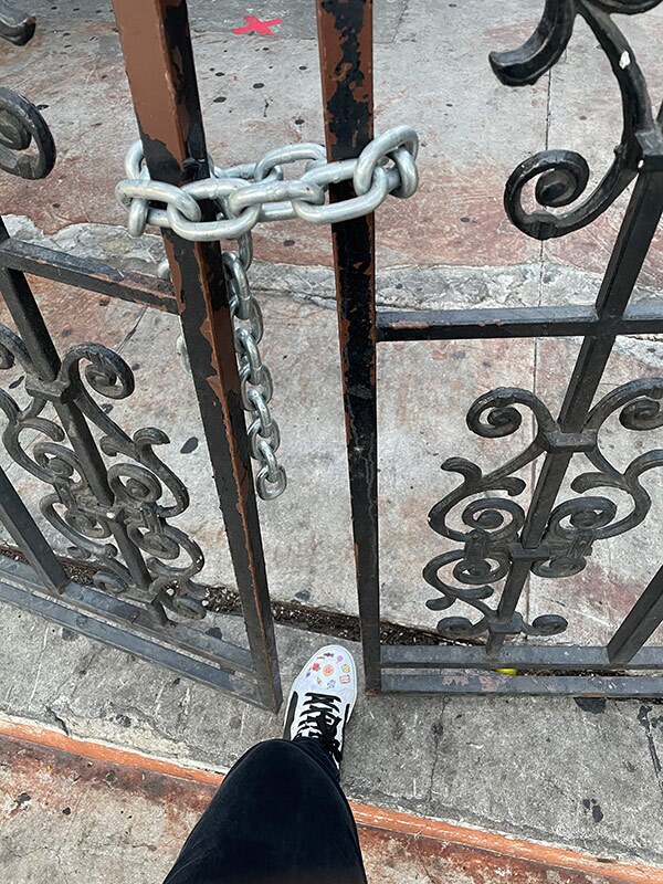 A person pushes one foot through a padlocked gate.