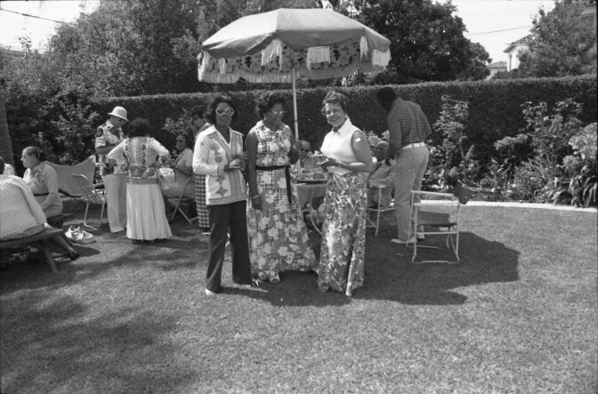 Men and women talking at a backyard garden party in Oakland, circa 1970s. | Oakland Public Library Digital Collections