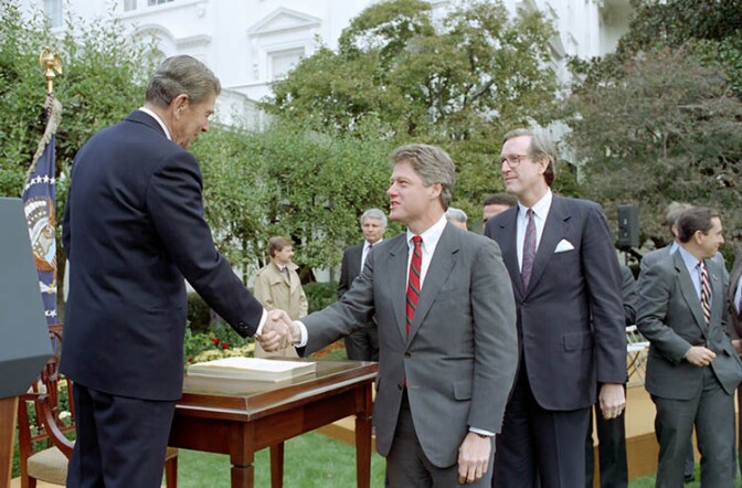 President Reagan shakes hands with Bill Clinton in the Rose Garden during signing ceremony for HR 1720 Welfare Reform Act of 1988, October 13, 1988.