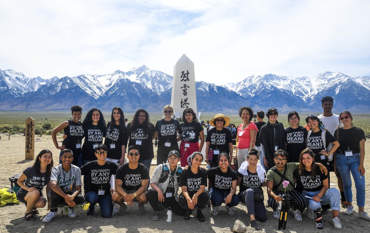 Members of Vigilant Love gather in front of a World War II monument for Manzanar Cemetery.