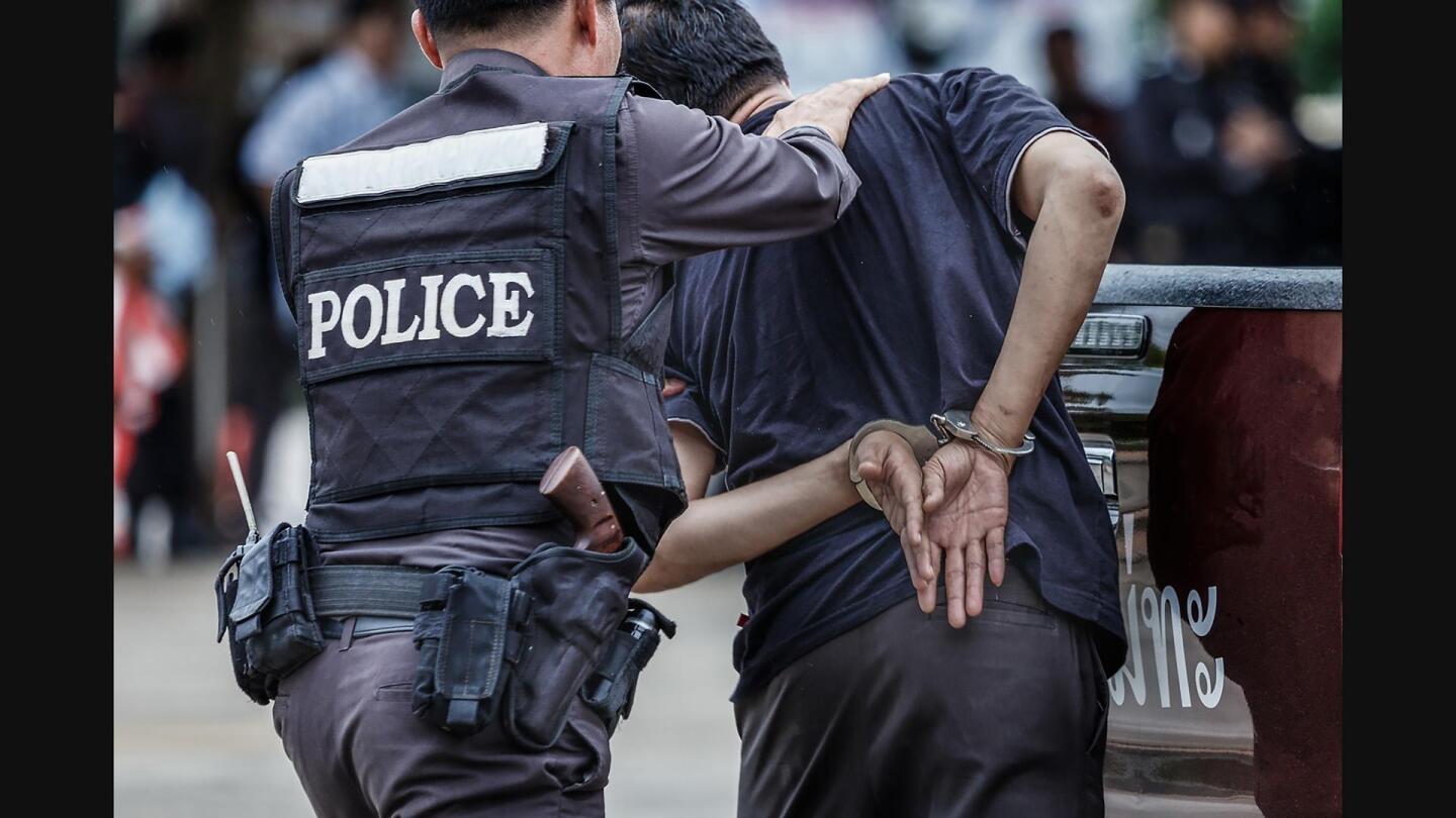 A police officer directing a man in handcuffs. | From "Hacking Your Mind: Us Vs. Them"