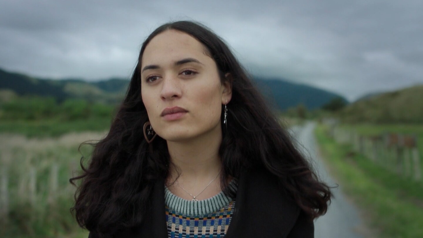 Te Awarangi "Awa" Puna, a transgender Maori teen, walks along a dirt road seen behind her.
