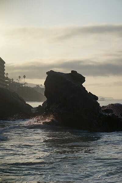A rock formation on the beach is bathed in light.