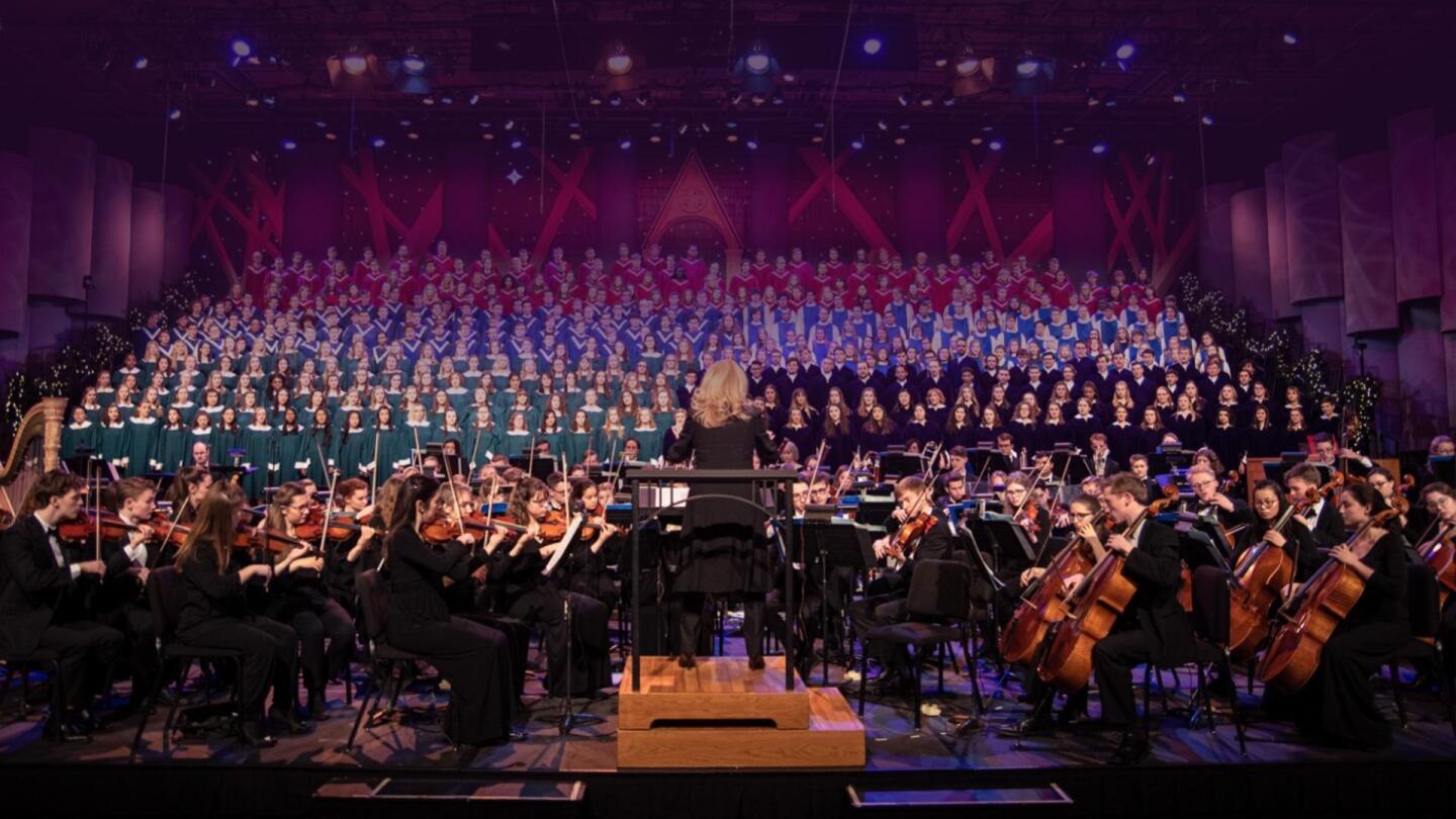 A conductor conducts an orchestra on stage.