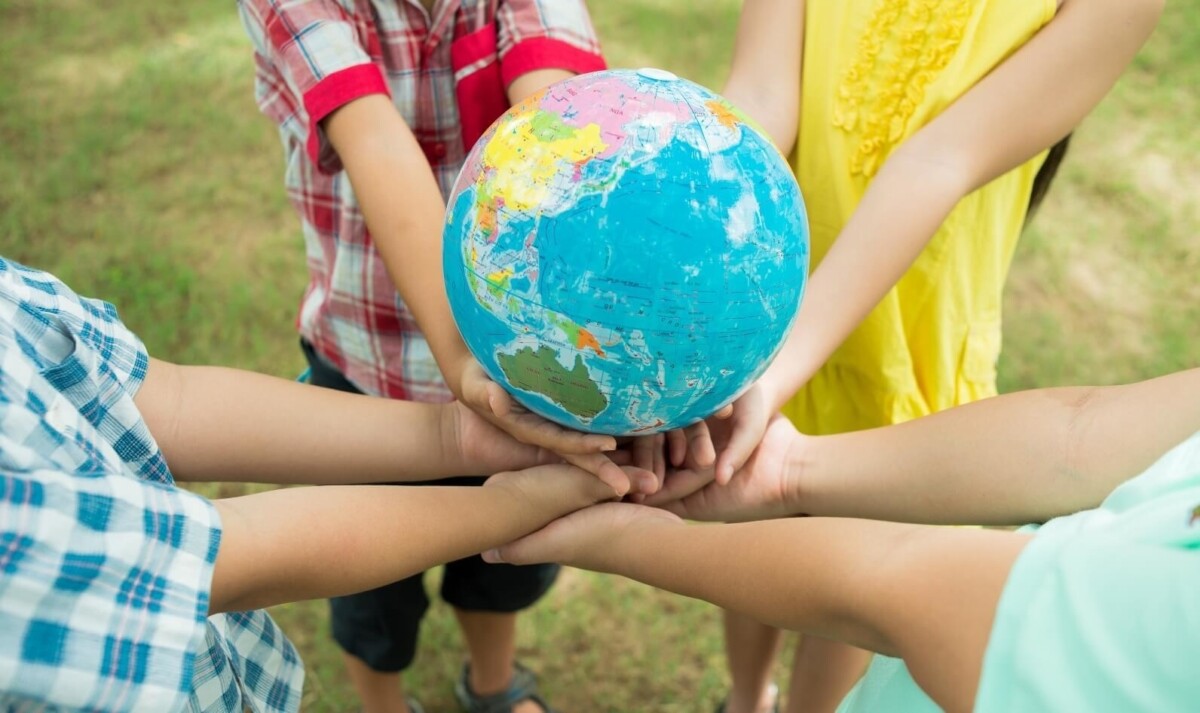Cuatro niños sostienen un globo terráqueo.