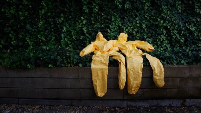 Yellow hazmat suits against a green background. | Thomson Reuters Foundation