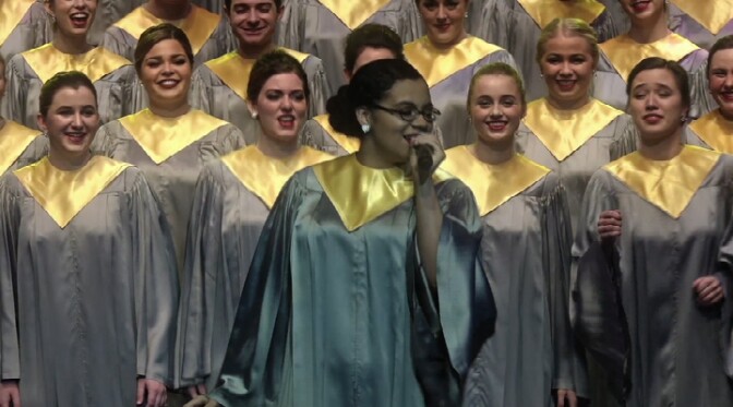 A woman sings a solo in front of a choir. | From "Purdue 86th Anniversary Christmas Show"