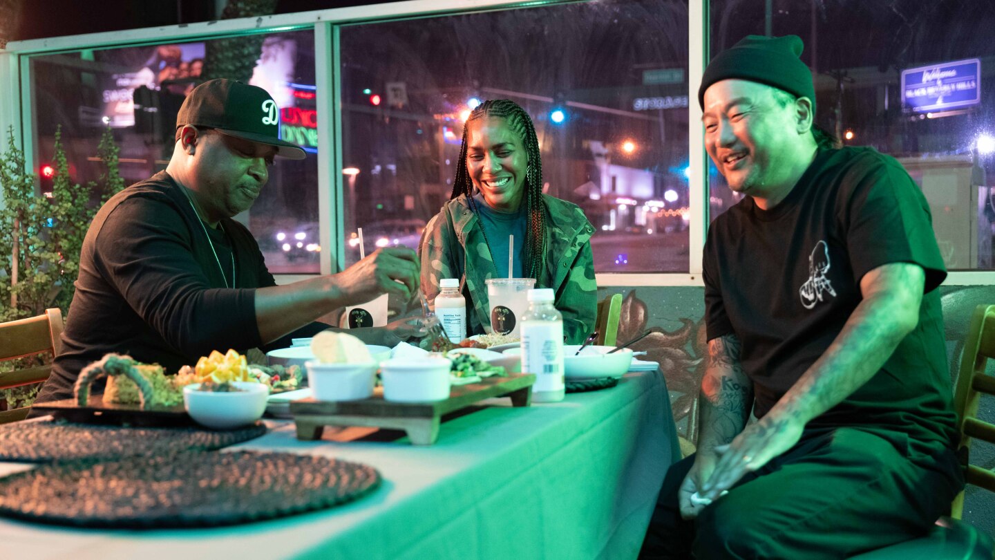 Three people eat food around a table.