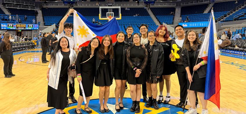 Fowler Out Loud: Tinig Choral, group of students in the UCLA basketball court holding flags and posing for picture 