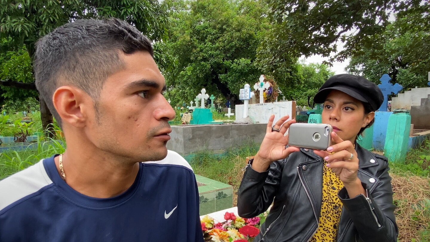 Filmmaker Adriana Trujillo (right) photographs Victor as the graveyard where he works in El Salvador.