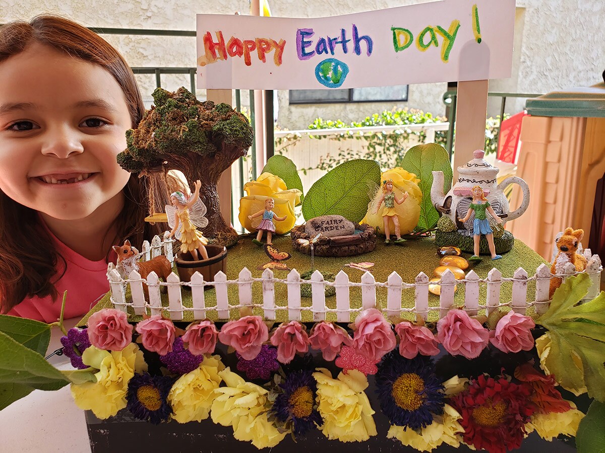 A smiling little girl poses with her Earth Day themed float made for the virtual Rosebud Parade.