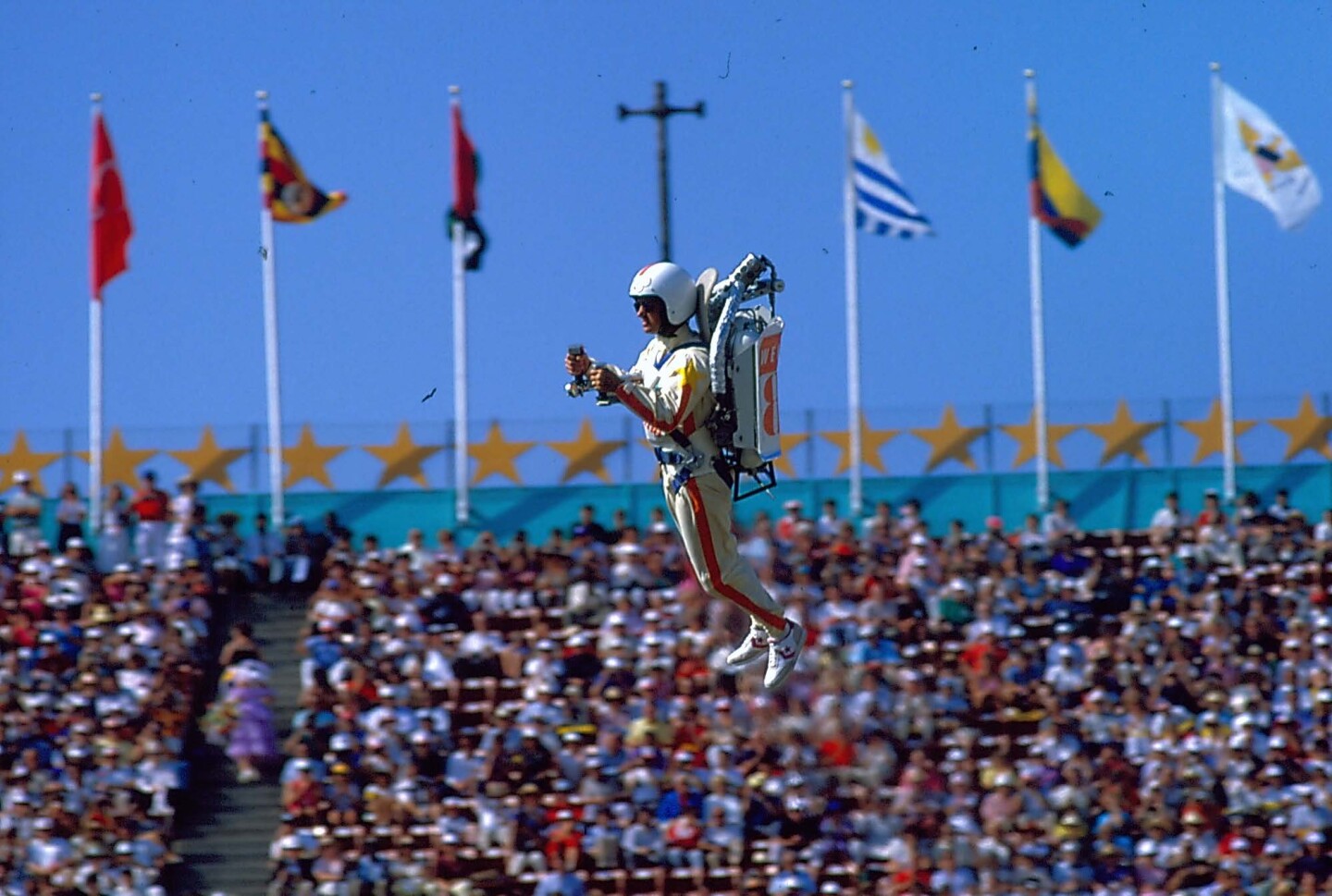 A man wearing a jet pack flies among the crowd during the 1984 Los Angeles Olympics opening ceremony.