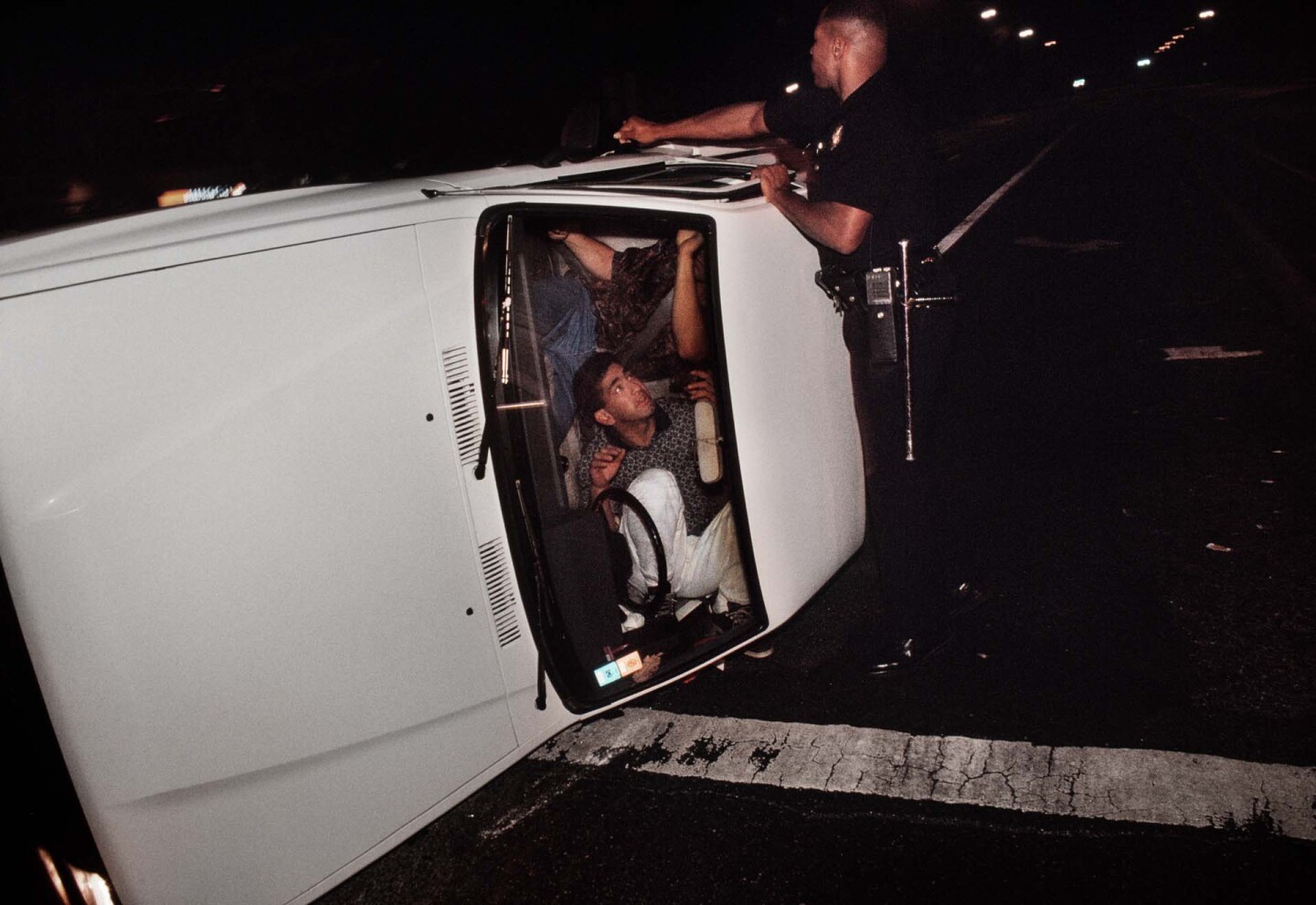 Pacific Division Officer Hoskins tries to pry open the door of a truck involved in a accident that left the driver and passenger locked in the overturned vehicle. | Joseph Rodriguez