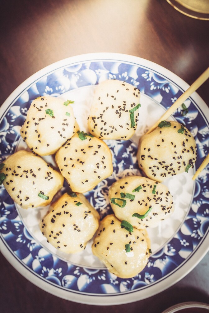 Eight pieces of sheng jian bao (pan-fried pork buns) in a plate.