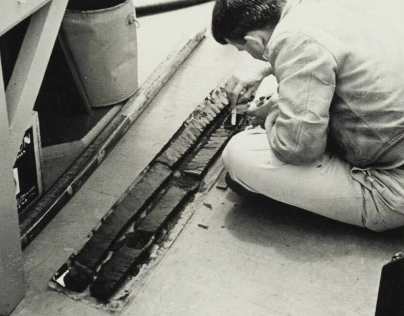 Dr. Thomas Clements examines seabed core sample, 1941. The core was obtained from a depth of several hundred fathoms by means of a coring device. | Allan Hancock Foundation Collection, USC Libraries