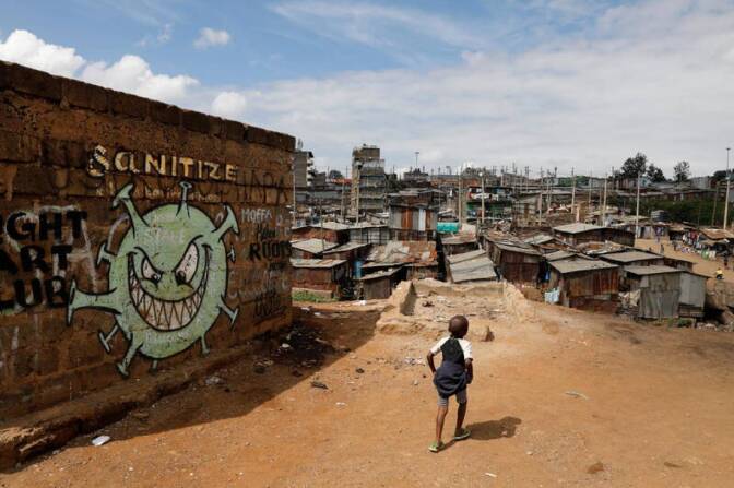 A boy walks in front of a graffiti promoting the fight against the coronavirus disease (COVID-19) in the Mathare slums of Nairobi, Kenya, May 22, 2020. | REUTERS/Baz Ratner