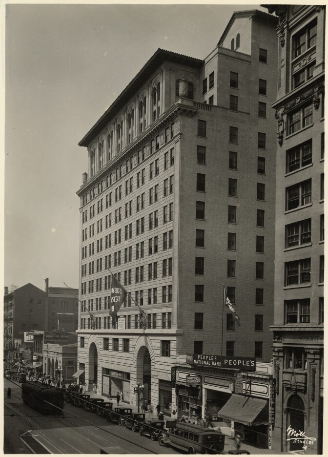 A black and white archival photo of the Subway Terminal Building — a tall building with uniform windows, spaced evenly apart. Two large arches serve as entrances at the bottom.