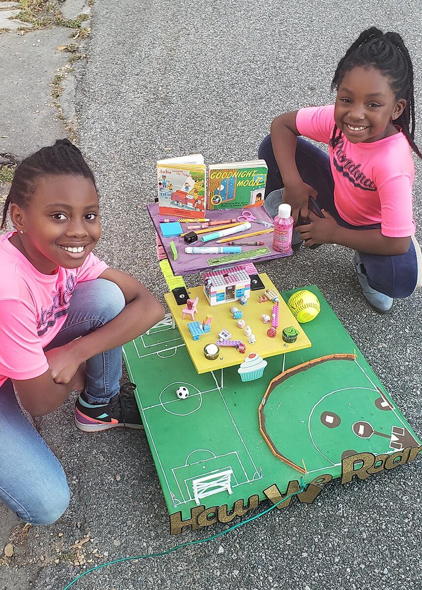 Two little girls work on a small parade float.