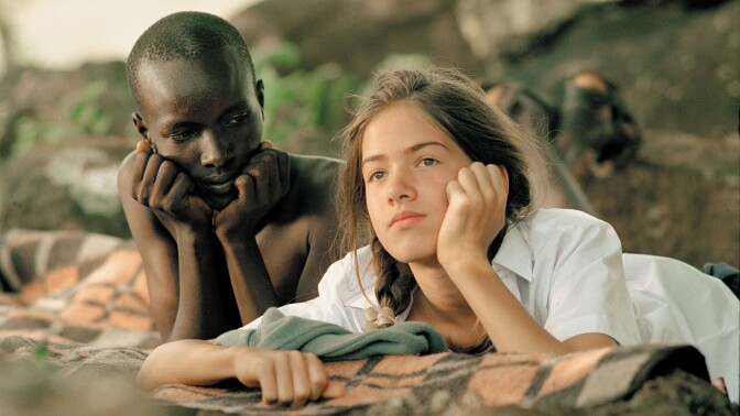 A boy looks at the girl lying next to him as she watches.