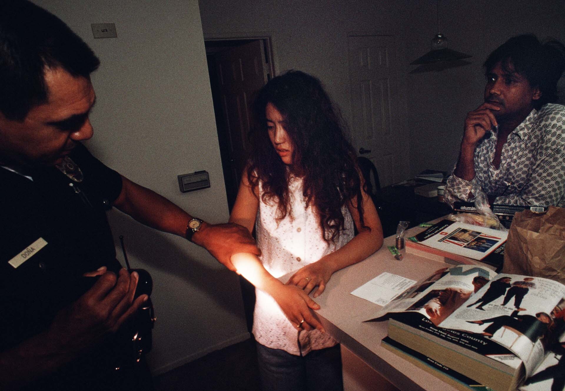 As her boyfriend looks on, a Japanese sex worker assaulted in her apartment shows Officer Dona her wounds. | Joseph Rodriguez