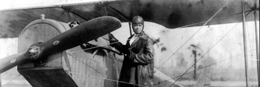 Bessie Coleman, shown here on the wheel of a Curtiss JN-4 “Jennie” in her custom-designed flying suit (circa 1924). | Smithsonian Institution