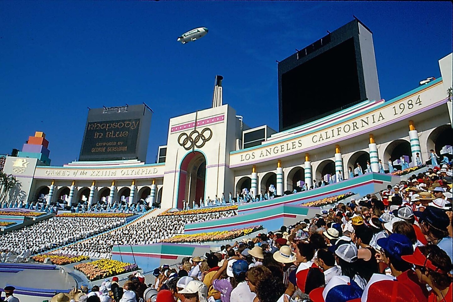 Large crowds at the 1984 Los Angeles Olympics opening ceremony. You can see columns decked out in the bright colors of the Olympics.