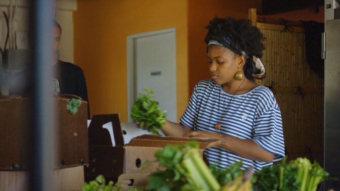 Olympia Auset arranging produce | Still from "Broken Bread" Access