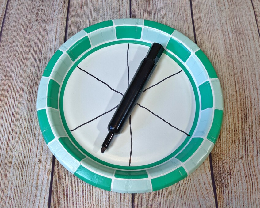A paper plate is divided into six slices with a black marker.