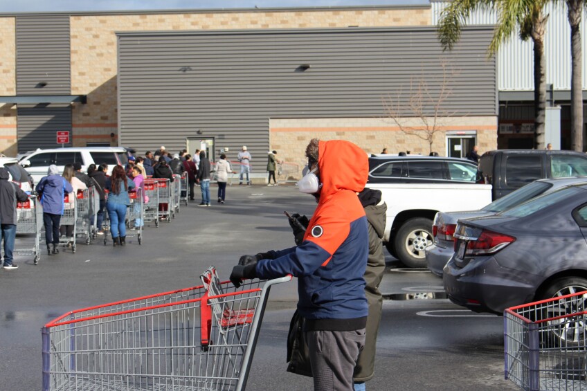 Man in orange sweatshirt with mask with a shopping cart, outside of Costco on March 15th, 2020