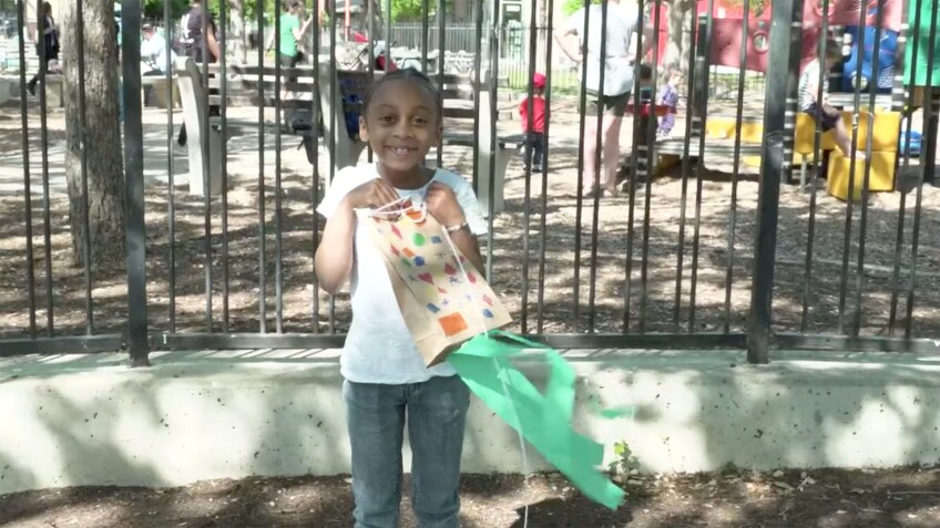 A little girl holds her homemade paper bag kite