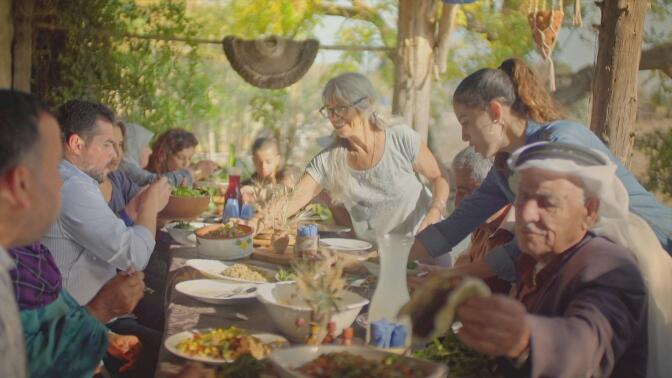 An Israeli family share a meal together on a long table.