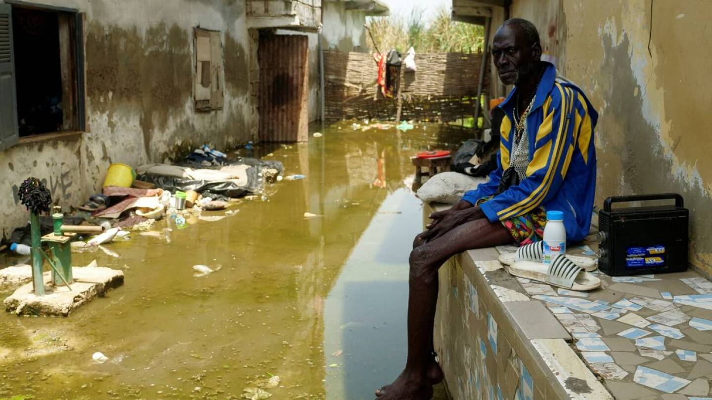 Issa Camara sits in the flooded alley of his home after heavy rains in Yeumbeul district on the outskirts of Dakar, Senegal, September 15, 2020. | REUTERS/Christophe Van Der Perre