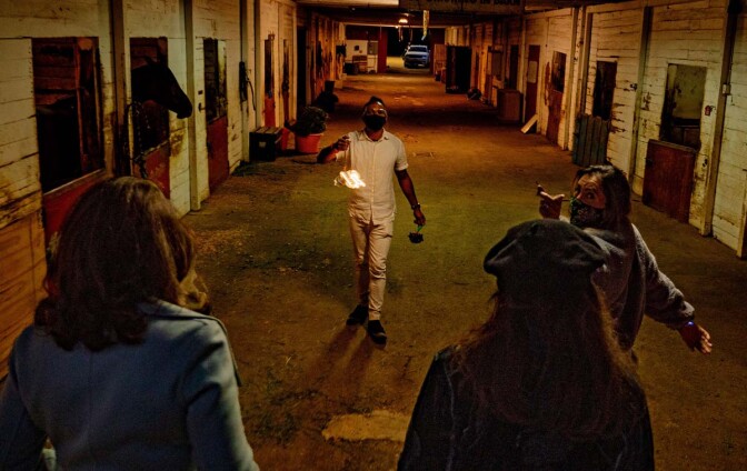 A performer holds a light in an alley. The performance is part of at "Firefly Nights," an in-person COVID-safe experience that falls within the "Rio Reveals" series.